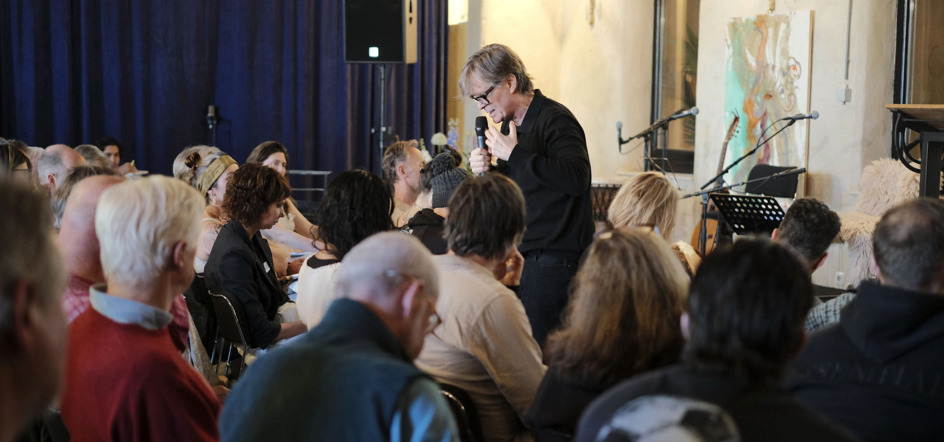 Dr. Marc Gafni speaking into a microphone before a seated audience