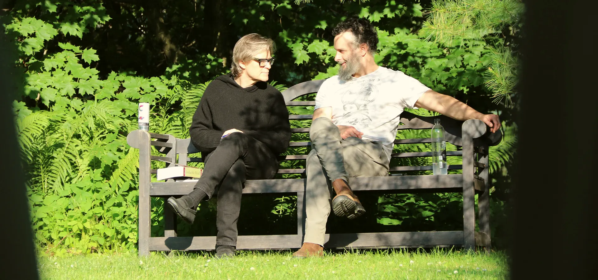 Dr. Marc Gafni and Dr. Zak Stein sitting together on a wooden bench in a garden, in conversation